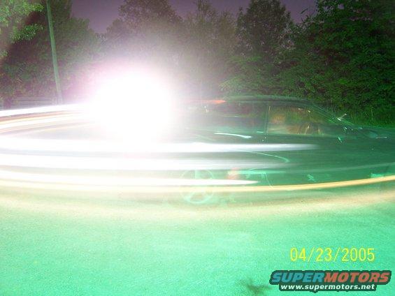 Car side view with light streaks from motion blur. Date stamp 04/23/2005 and "SUPERMOTORS" logo visible