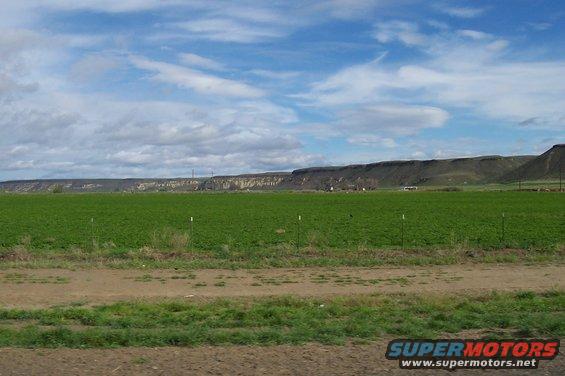 Farm field and distant hills under a cloudy sky