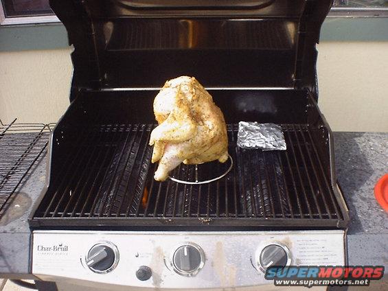 Raw chicken on a rotisserie stand on a Char-Broil gas grill
