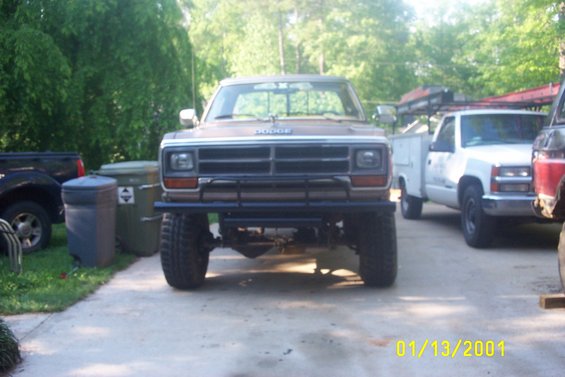 Brown Dodge pickup truck with a brush guard, lifted suspension, and large tires