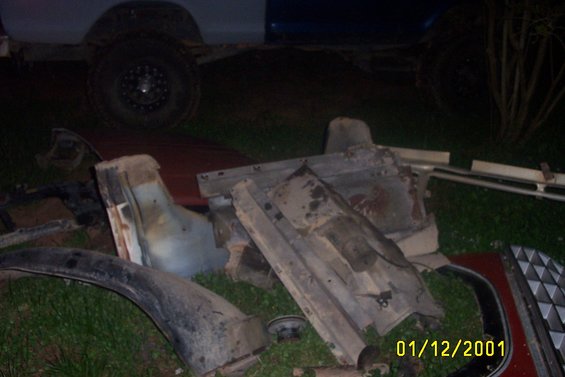 Scattered vehicle parts including a fender and grille, with a date stamp of 01/12/2001