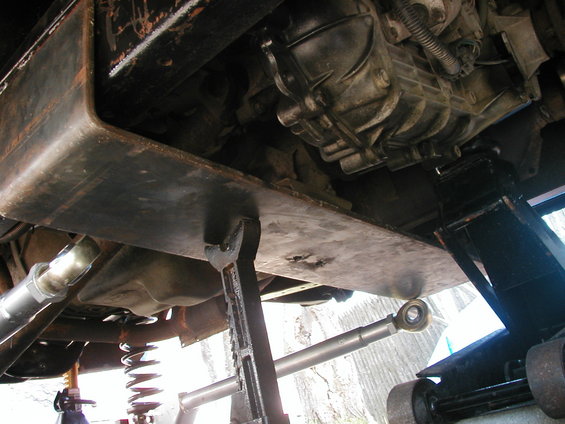 Vehicle underbody with skid plate and transmission visible, supported by jack stands