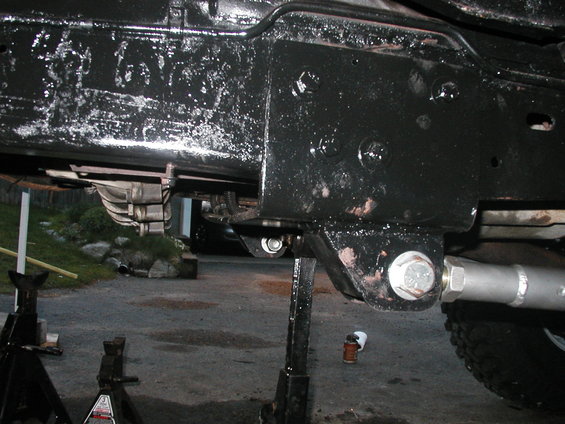 Underside of a vehicle on jack stands, showing frame, suspension, and drivetrain parts