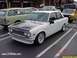 1986 Ford Bronco - A white Datsun 510 sedan is parked in a lot with other vehicles visible.