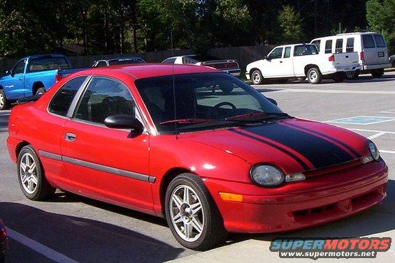 Red coupe with black racing stripes, front quarter view. Appears to be a Dodge Neon