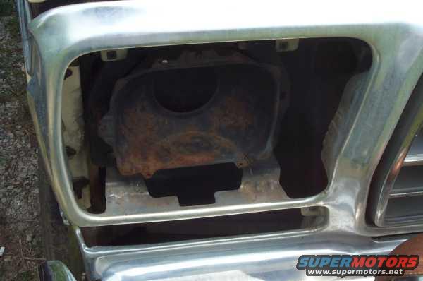Close-up of a vehicle's front grille opening, showing rusty internal components