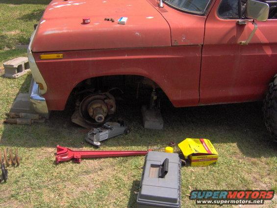 1979 Ford Bronco with front wheel off, jacked up, and tools on the ground