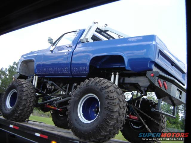 Blue monster truck with large tires and 'DARRELL CORE DOZER SERVICE' text on the side