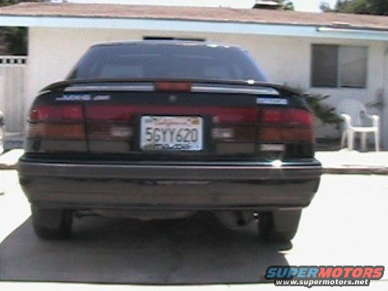 Rear view of a black 1989 Mazda MX-6 with a spoiler and California plates