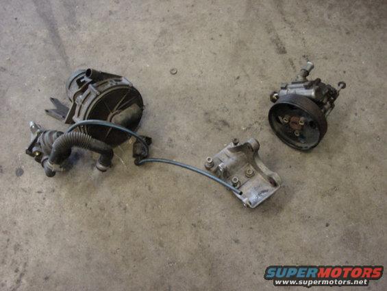 Three automotive parts, including a power steering pump, on a concrete floor