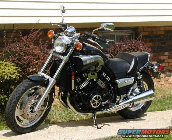 1999 Yamaha V-Max motorcycle parked on a sidewalk in front of a brick house