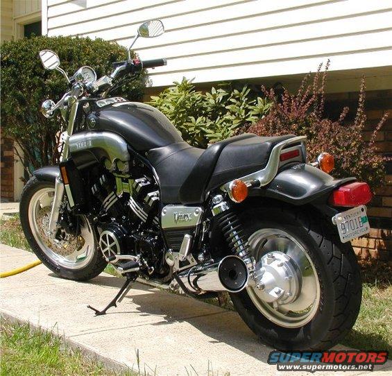 Black Yamaha V-Max motorcycle parked on a sidewalk next to a house