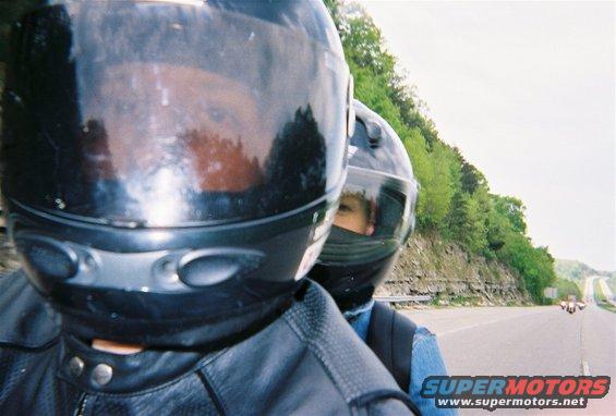 Two helmeted riders on a motorcycle on a highway
