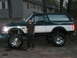 1994 Ford Bronco - A person stands next to a lifted Ford Bronco, which appears to be from the early to mid-1990s.