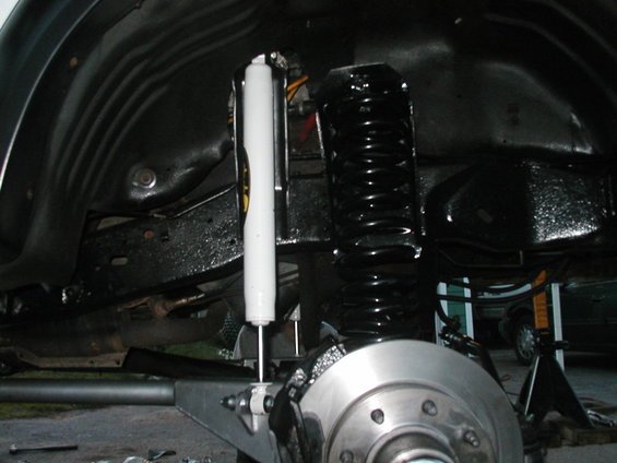 Close-up of a vehicle's front suspension with a white shock absorber and black coil spring