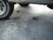 1987 Ford Bronco - Close-up of a vehicle's lower body and tire, showing stains on the ground below.