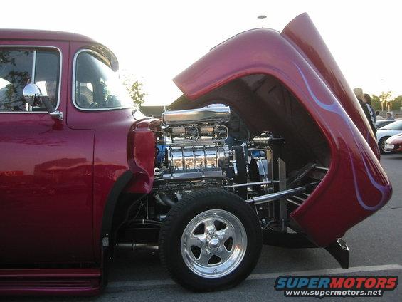 Red hot rod with hood open, showing a chrome supercharged engine and purple flames on the hood