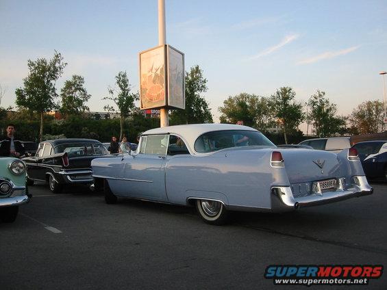 Light blue classic Cadillac with a white roof parked in a lot, rear view. License plate P6588R