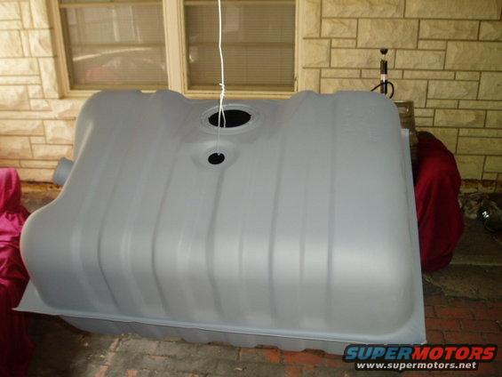 Gray plastic fuel tank with two circular openings on top, suspended by a white string