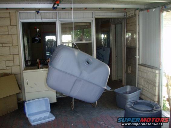 Gray fuel tank suspended by a rope, indoors