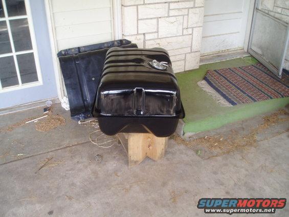 black fuel tank on wooden blocks, another black part behind it