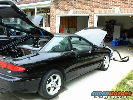 Black 1994 Ford Probe with open hood and trunk, parked in driveway