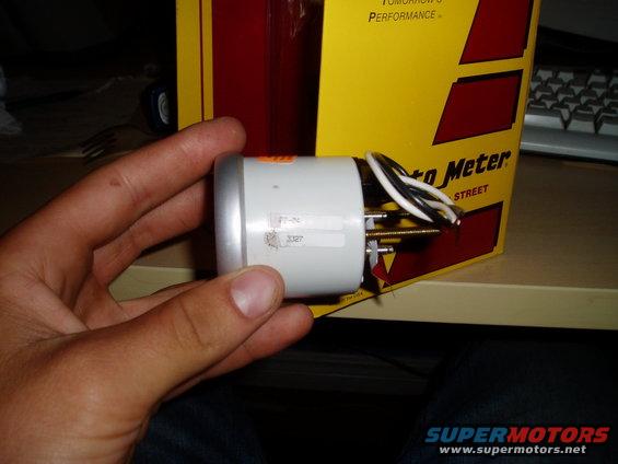 White oil pressure gauge with silver bezel and wires, held in hand