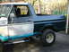 1979 Ford Bronco - This 1979 Ford Bronco is undergoing a paint job, with one side showing primer and the other a dark teal color, revealing some rust damage.