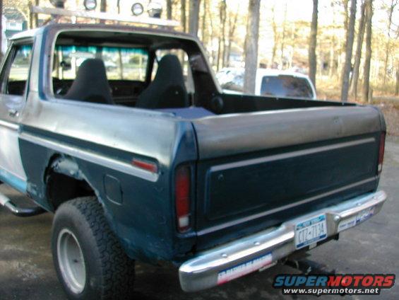 1978 Ford Bronco rear view, showing custom roof rack, interior seats, and aftermarket bumper stickers
