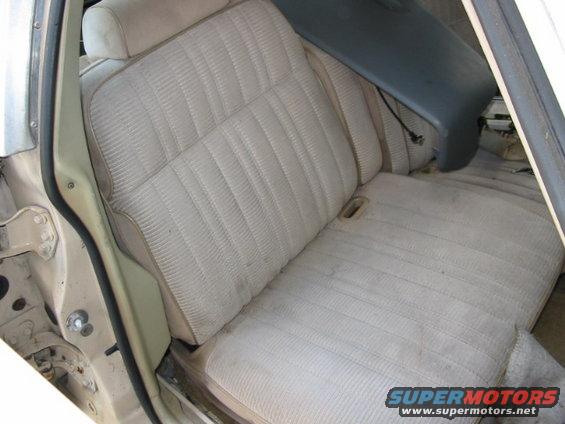 Interior view of car seats, showing beige fabric upholstery and a dark blue trim piece