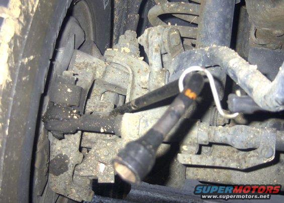 As I was doing this project "Lone Ranger" style, I needed to apply outward pressure
on the axle shaft u-joint. The only way I could quickly resolve this was to place a
standard crow bar behind the u-joint and using a black rubber tie-down strap to
pull tension on the crow bar. I simply hooked the other end to the Pittman arm