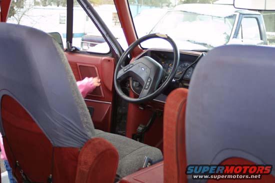 Interior shot of a van, showing seats and steering wheel. Another vehicle is visible through the windshield