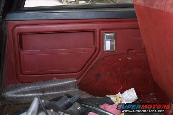 Red interior door panel and carpeted rear cargo area of a vehicle