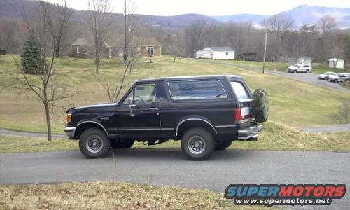 Black Ford Bronco parked on a road with houses and hills in the background