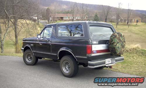 Black Ford Bronco with camouflage spare tire on rear, parked on asphalt road