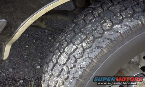 Close-up of a tire and fender flare with Supermotors.net logo
