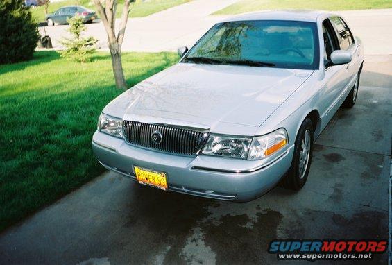 Silver Mercury Grand Marquis parked on driveway. Yellow license plate reads 'POWER 99'