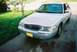 2000 Ford Crown Victoria - A silver Mercury Grand Marquis is parked on a driveway, with a grassy lawn and another car in the background.