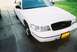 2000 Ford Crown Victoria - A white 2000 Ford Crown Victoria is parked on a concrete driveway with green grass in the background.