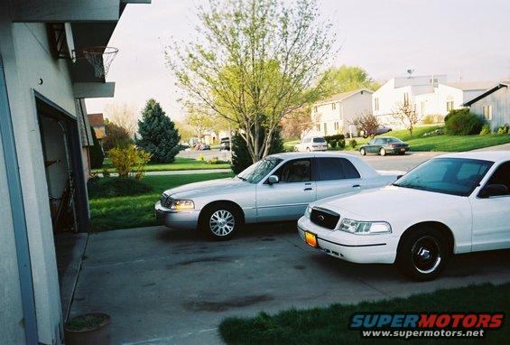 Silver and white 2000 Ford Crown Victoria sedans parked in driveway