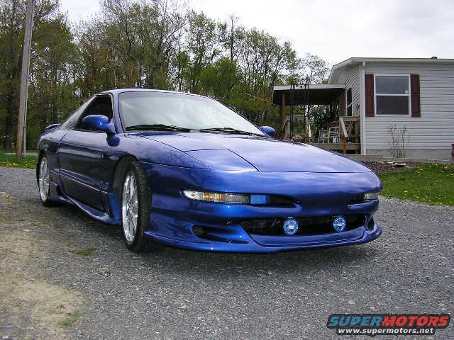Blue 1994 Ford Probe coupe with aftermarket body kit and fog lights parked on gravel