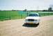 2000 Ford Crown Victoria - A white 2000 Ford Crown Victoria is seen from a 3/4 front view, parked on a gravel lot next to a fenced-in sports field.