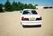 2000 Ford Crown Victoria - A white sedan is parked in a gravel lot with trees and a building in the background.