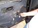 2003 Ford Ranger - Close-up of a vehicle's interior door panel with the speaker removed, revealing wiring and the door handle mechanism.