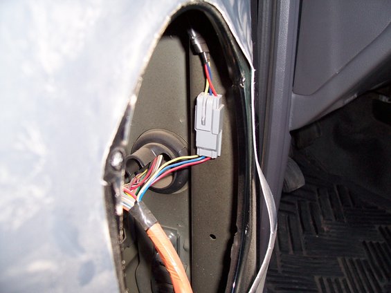 Close-up of a vehicle's wiring harness with multiple colored wires and a grey connector