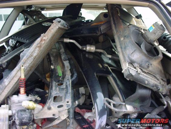 Pile of car parts, including a black dashboard section and metal bracing, filling the interior of a vehicle
