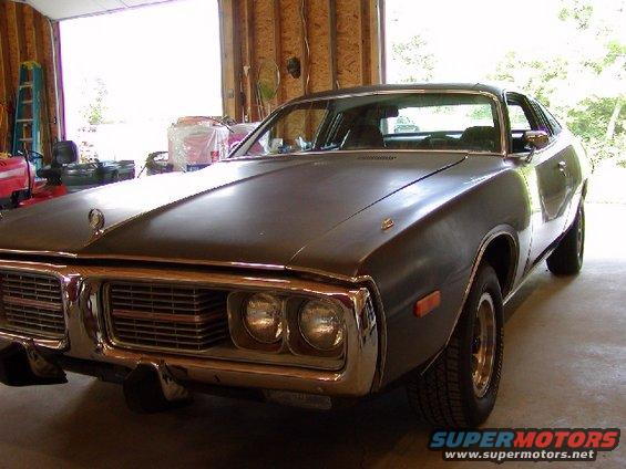 Dark gray 1973 Dodge Charger in a garage, front 3/4 view. Chrome grille and bumper, dual headlights
