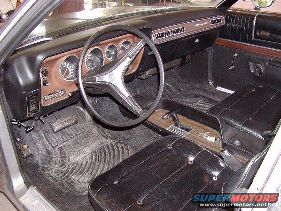 Interior view of a 1973 Dodge Charger with black seats and woodgrain trim