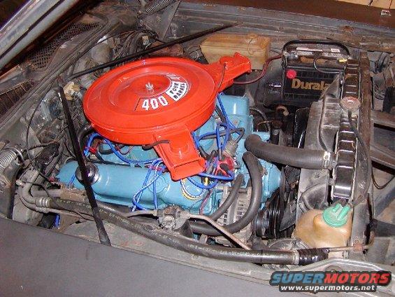 Engine bay with a blue engine block, orange air cleaner with '400 FOUR BARREL' text, and a Duralast battery