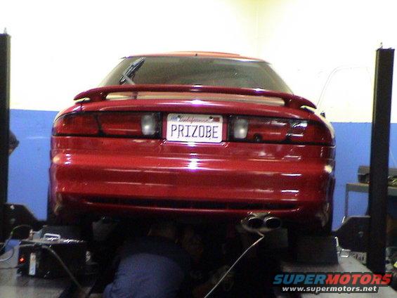 red coupe on lift, rear view, custom license plate reads PRIZOBE